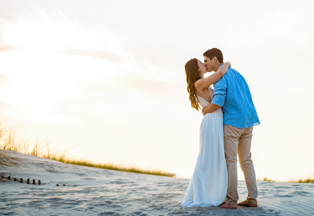 couple shares a kiss on the shores of wildwood New Jersey during their beach engagement session