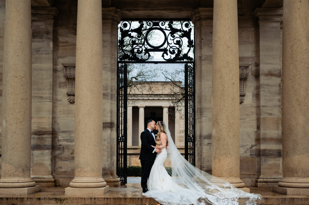 bride and groom kissing in front of the gate