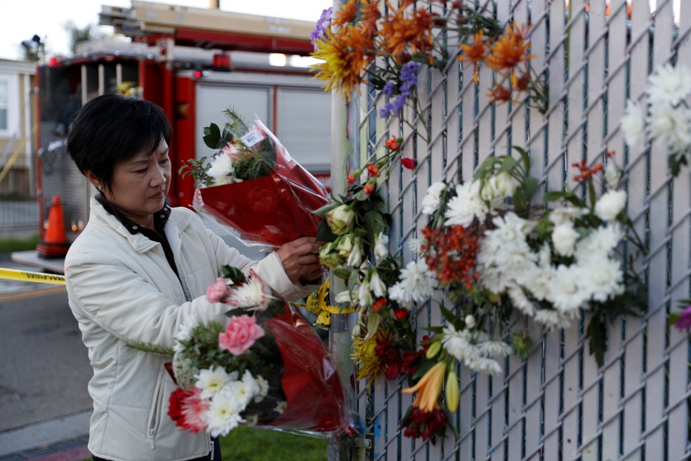 Mulher coloca flores em um memorial improvisado perto de onde ocorreu o incêndio em Oakland, na California (Foto: Stephen Lam/Reuters)