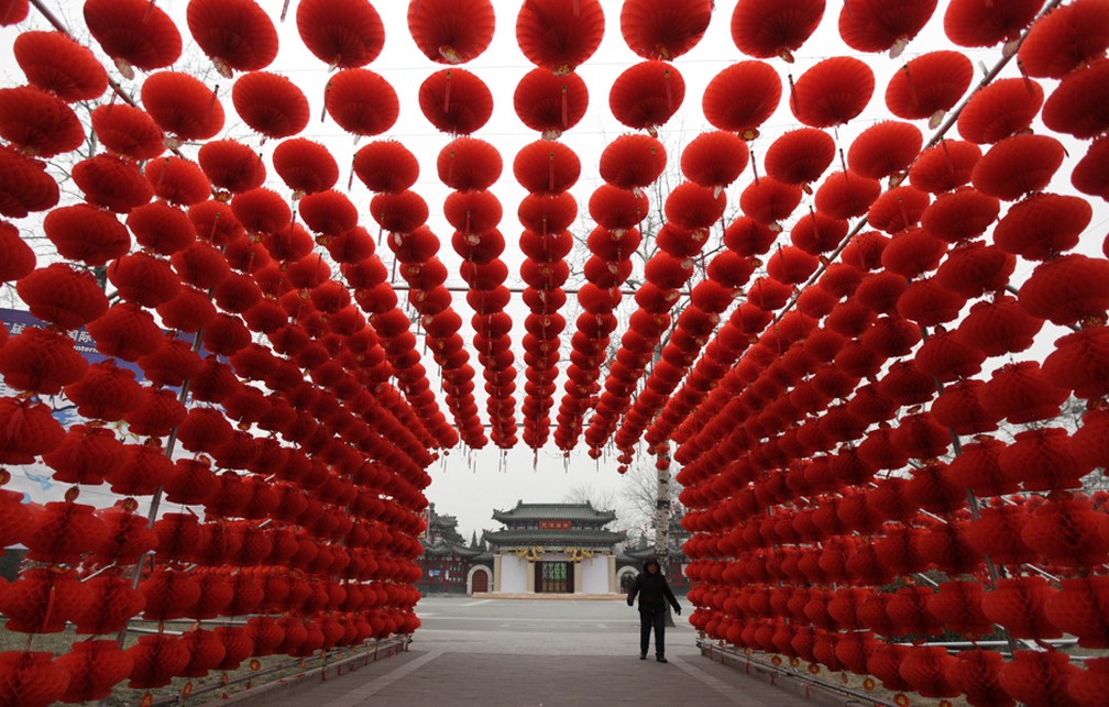 Mulher passa por lanternas vermelhas colocadas como decoração para uma feira do templo em uma entrada do parque Longtan em Pequim em 2016 — Foto: Reuters