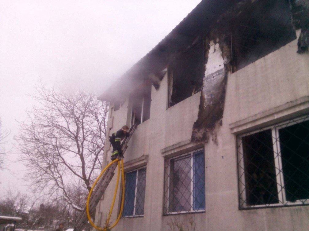 Socorrista tenta entrar pela janela da residência para idosos atingida por um incêndio na Ucrânia em 21 de janeiro de 2021 — Foto: Serviço de Emergência da Ucrânia/Reuters