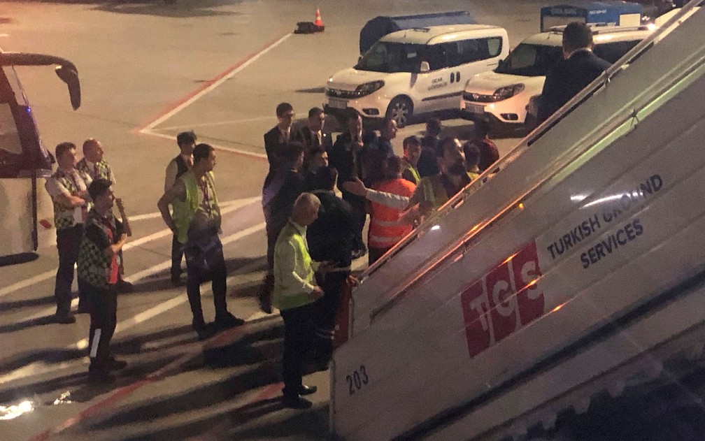 Escoltado por seguranças e policiais, passageiros desembarca em Istambul após provocar tumulto em voo da Turkish Airlines entre Istambul e Cartum, na sexta-feira (14) — Foto: AP Photo/Hussein Malla