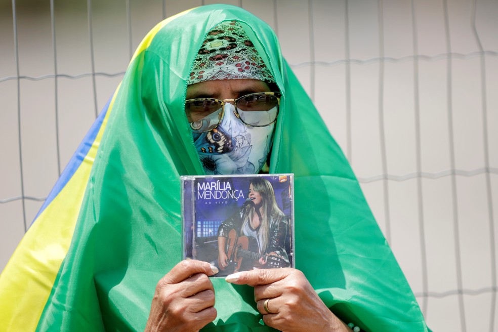 Fã da cantora Marília Mendonça segura um CD enquanto aguardava velório. — Foto: REUTERS/Ueslei Marcelino
