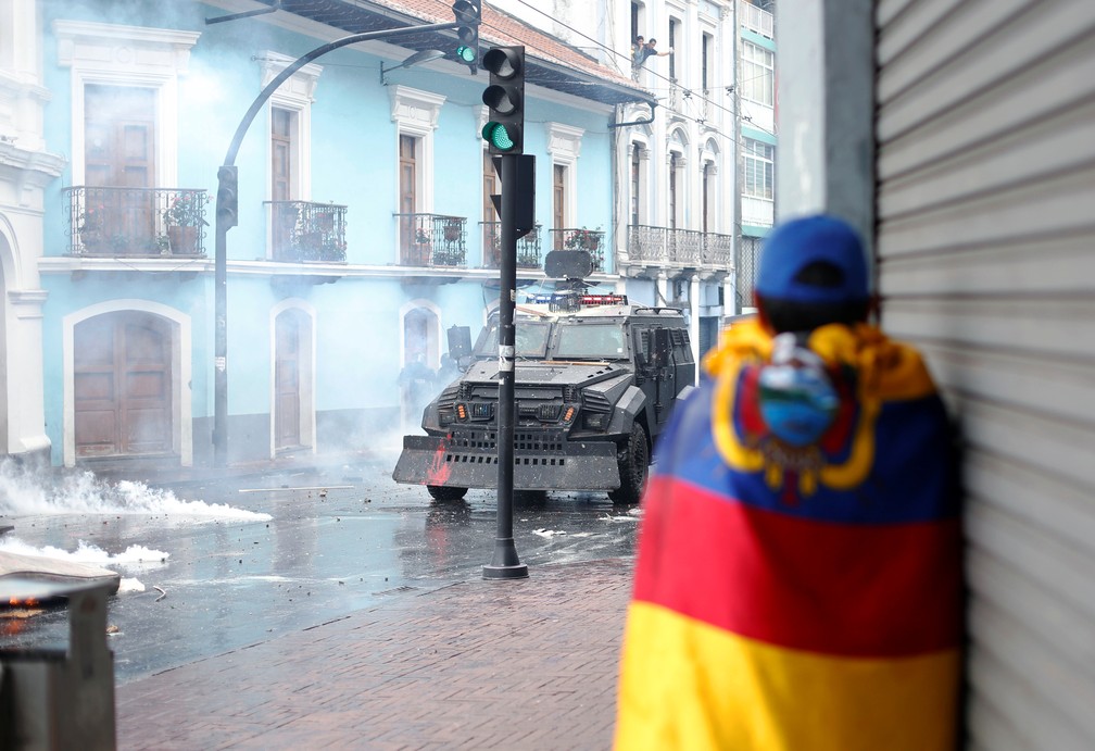Manifestante enrolado em bandeira do Equador acompanha protestos em Quito contra aumento dos combustíveis — Foto: Daniel Tapia/Reuters
