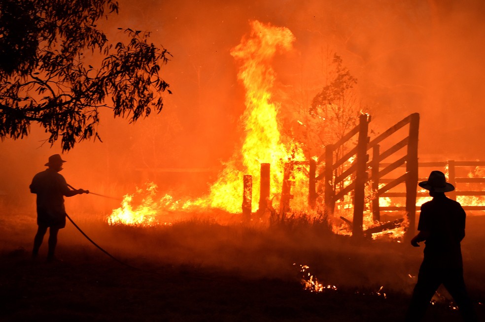 Moradores tentam apagar incêndio em Hillsville, cerca de 350 km ao norte de Sydney, no dia 12 de dezembro. — Foto: Peter Parks / AFP