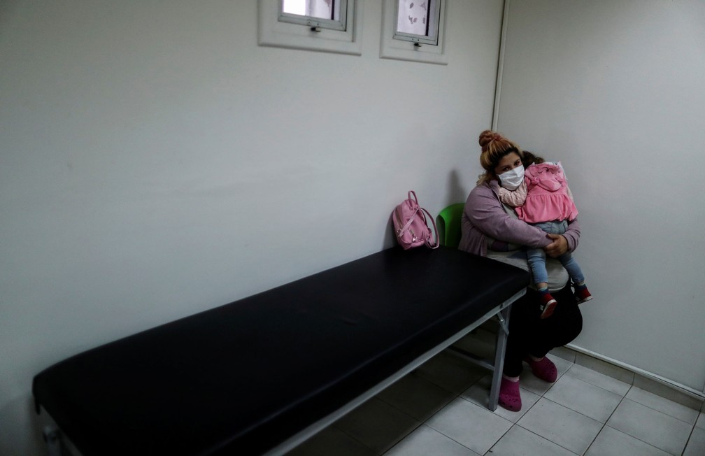 Mulher segura no colo filha infectada pelo novo coronavírus, em hospital em Ezeiza, nos arredores de Buenos Aires, na Argentina  — Foto: Agustin Marcarian/ Reuters
