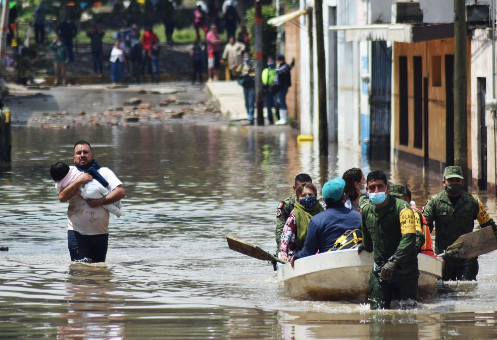 Pessoas saem de hospital inundado no México em botes ou a pé nesta terça-feira (7) — Foto: Francisco Villeda/AFP
