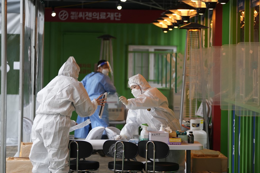 Profissionais de saúde vestindo equipamentos de proteção se preparam para coletar amostras em uma clínica temporária de triagem para o coronavírus em Seul, Coreia do Sul, nesta quarta-feira (29). — Foto: Lee Jin-man/AP