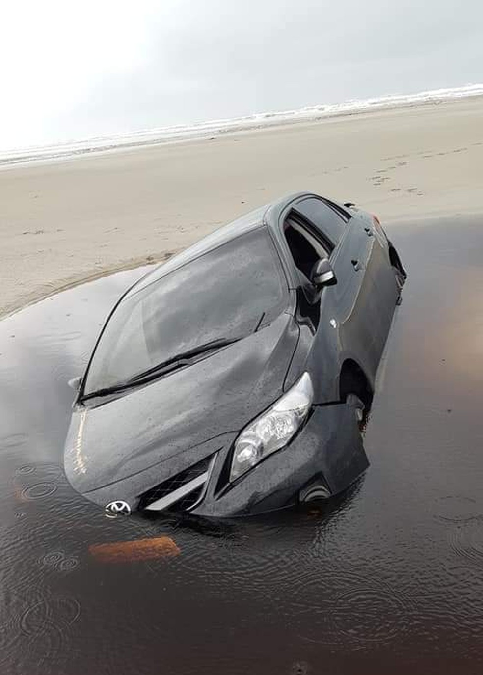 Carro atolado na faixa de areia foi tomado pelo mar em Ilha Comprida, SP — Foto: Arquivo pessoal/José Soares Bender