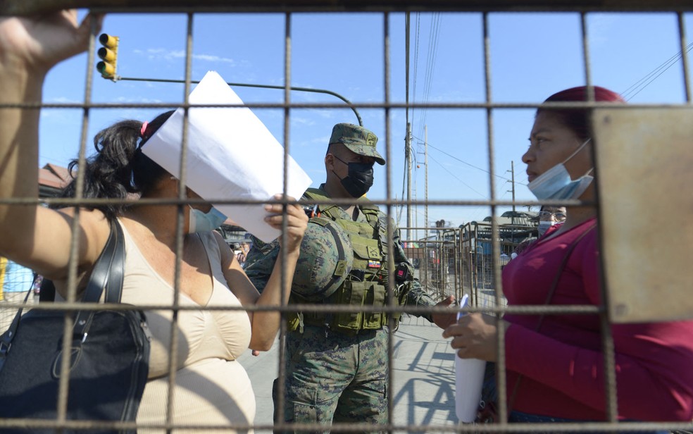   Parentes de detentos conversam com soldado enquanto aguardam notícias do lado de fora de penitenciária em Guayaquil, no Equador, na quarta-feira (29) — Foto: Fernando Mendez/AFP 
