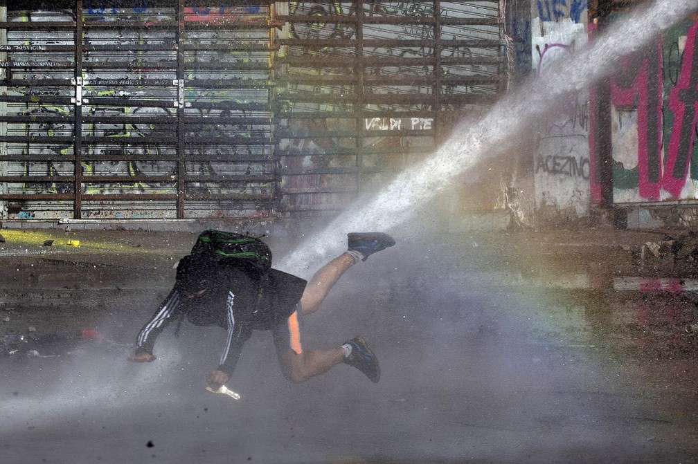 Manifestante atingido por jato de água em Santiago, em 26 de novembro de 2019 — Foto: Claudio Reyes / AFP