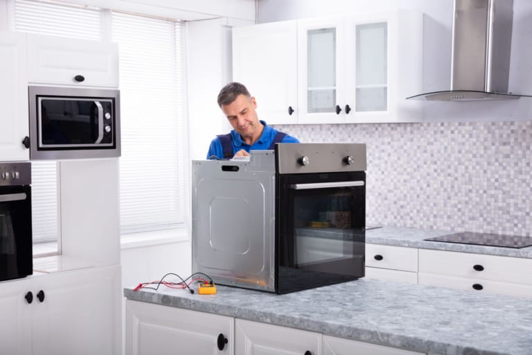 Mature Male Technician Repairing Oven On Kitchen Worktop with FHA 203(k) funds