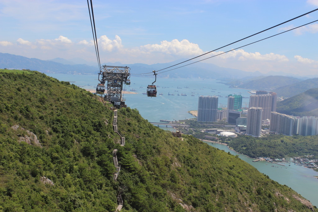 Lush mountainside view of Ngong Ping Cable Car with Tung Chung in the background.