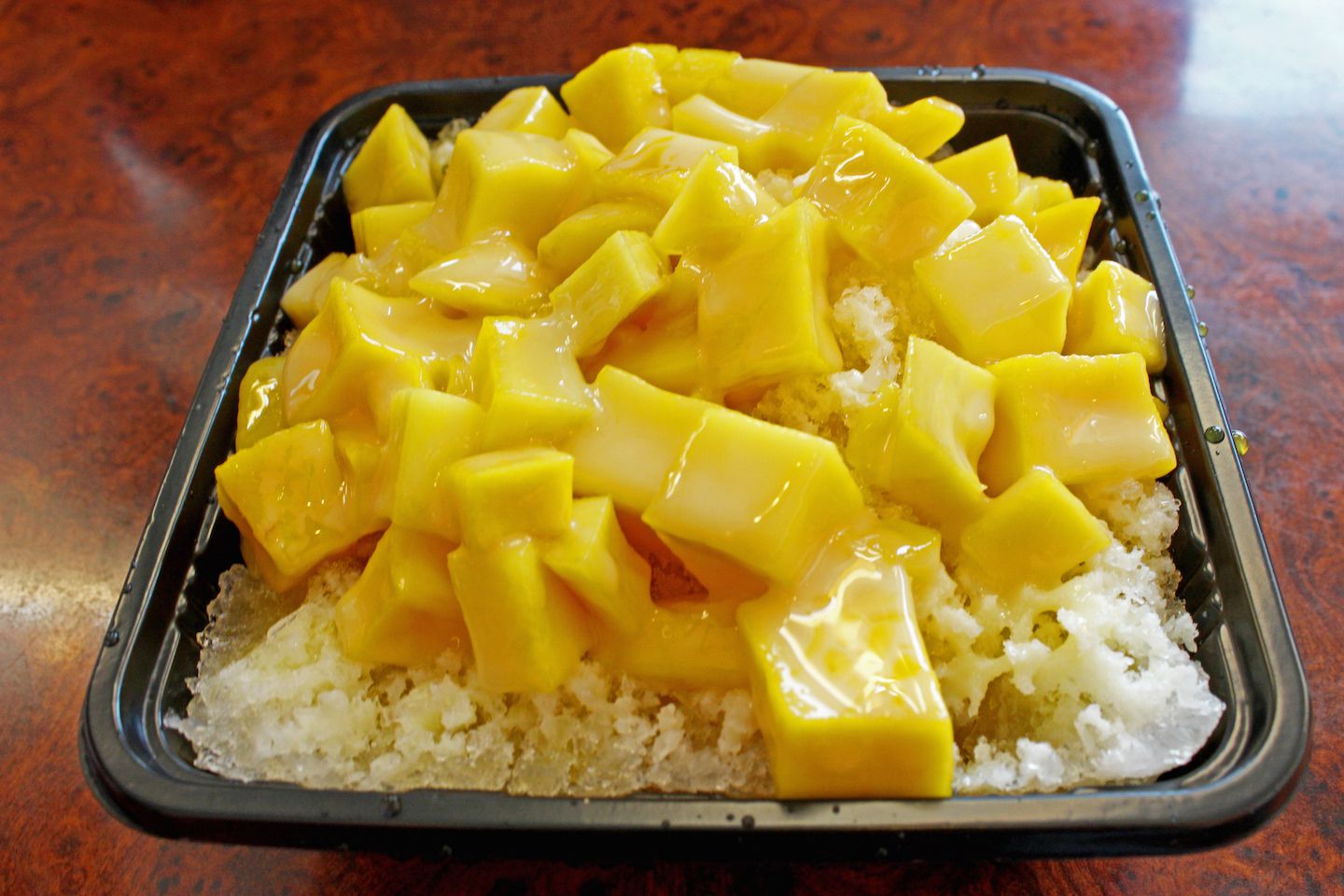 Mango shaved ice with ice chunks and mango pieces