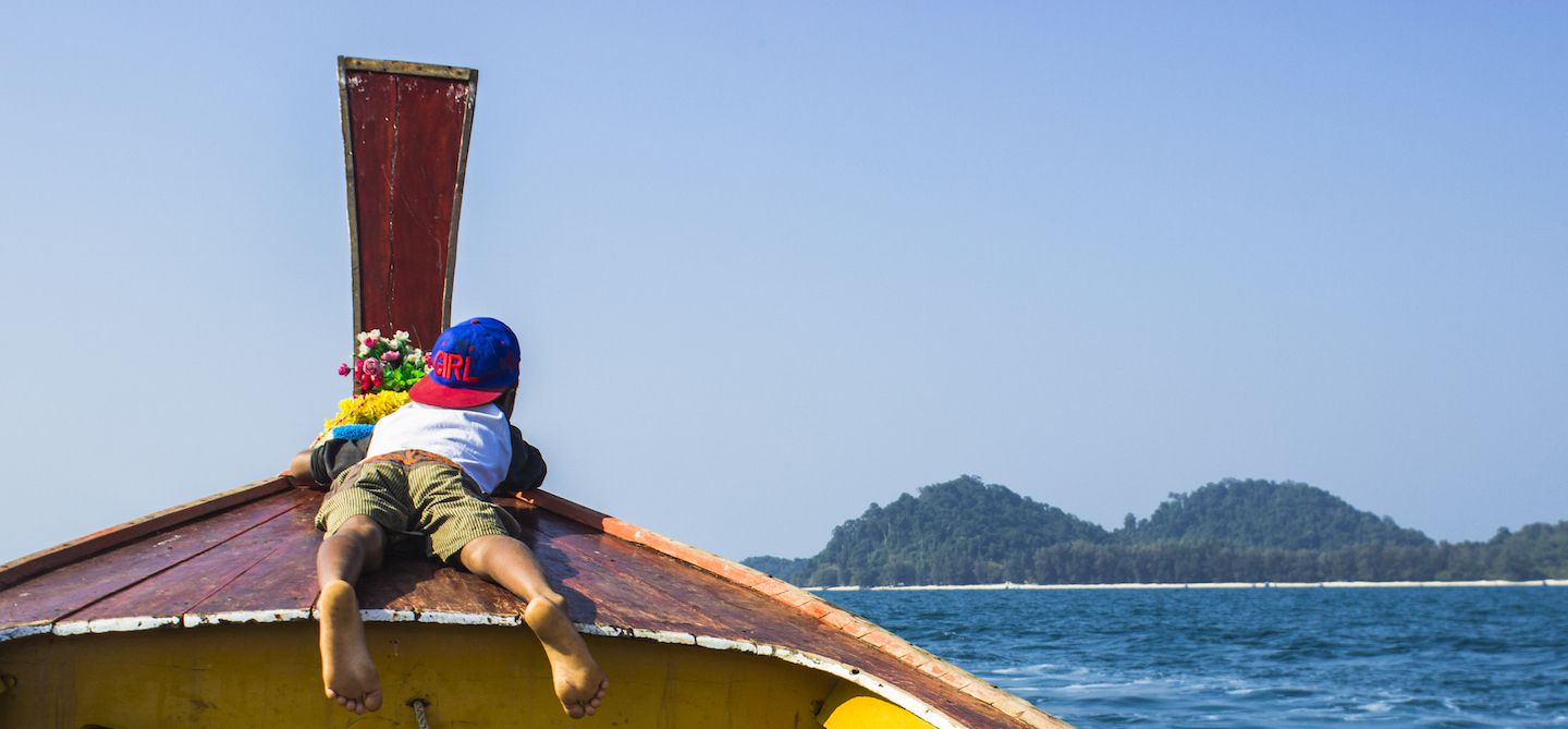 Our boat driver kid lounging on the longtail boat deck to the Emerald Cave, Koh Muk, Thailand