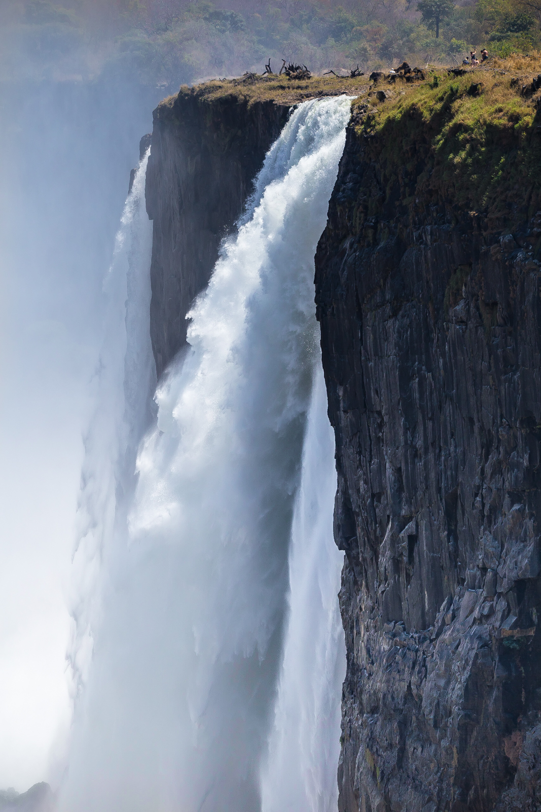 People standing at Devil's pool, right above the fall, Victoria Falls, Zimbabwe.
