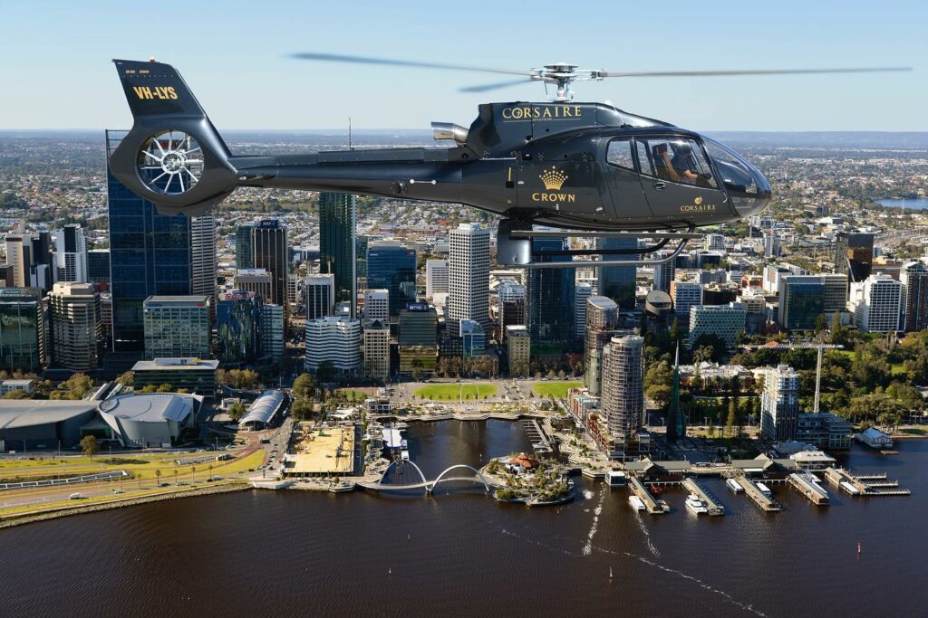 A black Corsaire helicopter flying in front of Perth City and the Swan River