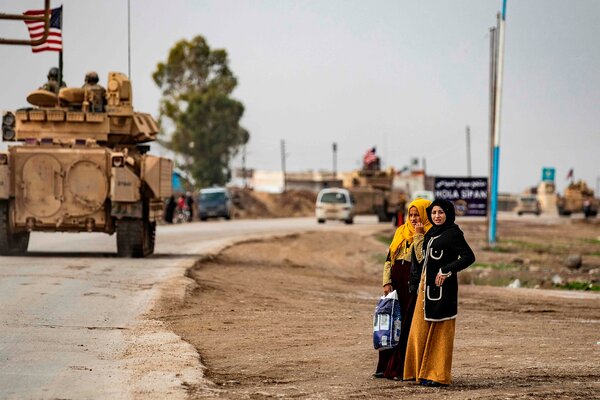 Women watched U.S. troops patrol  the roads of the northeastern Syrian town of Al Jawadiyahin, near the border with Turkey, on Thursday. The coronavirus is surging in Syria, which has little capacity to cope with another crisis.