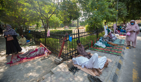 Patients and their relatives rest on the sidewalk near Holy Family Hospital, one of the busiest government hospitals and a treatment center for Covid-19, in Rawalpindi, Pakistan.