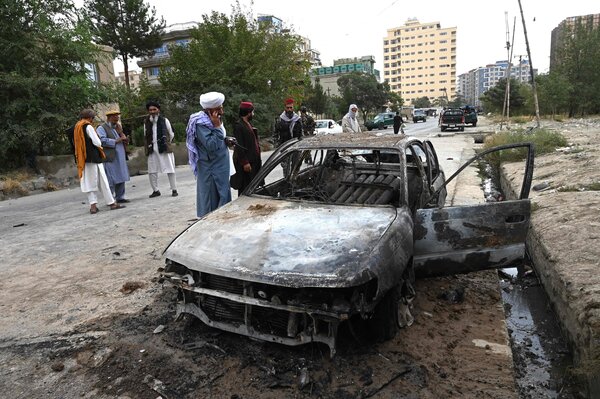 Taliban fighters investigating a damaged car after multiple rockets were fired in Kabul on Monday.