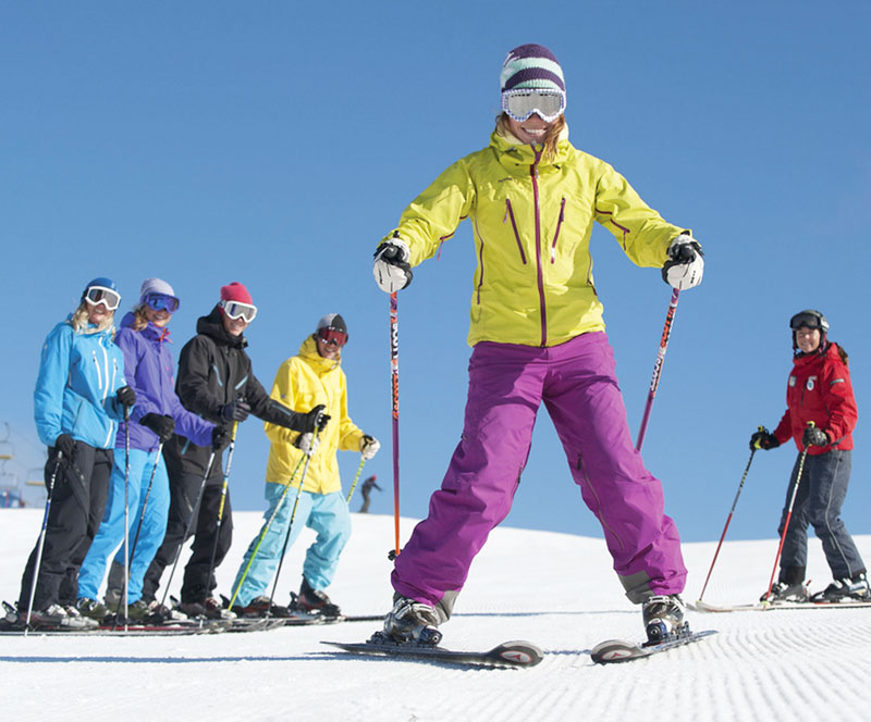 Smiling woman learns to ski in ski school GROUP LESSON