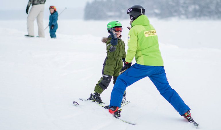 smiling child high-fives private ski instructor