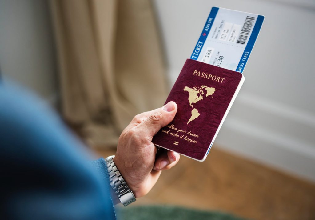 male hand holding passport and airline tickets