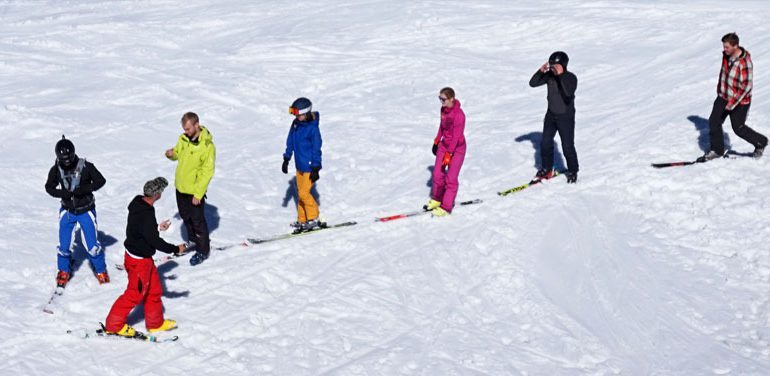 ski instructor teaches first timer adult skiers the one foot ski shuffle