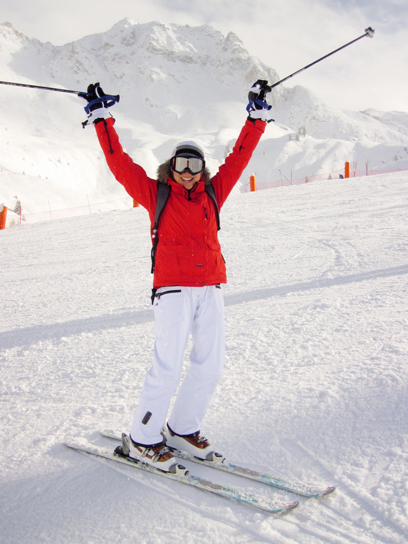 Adult beginner skier celebrates with arms in air