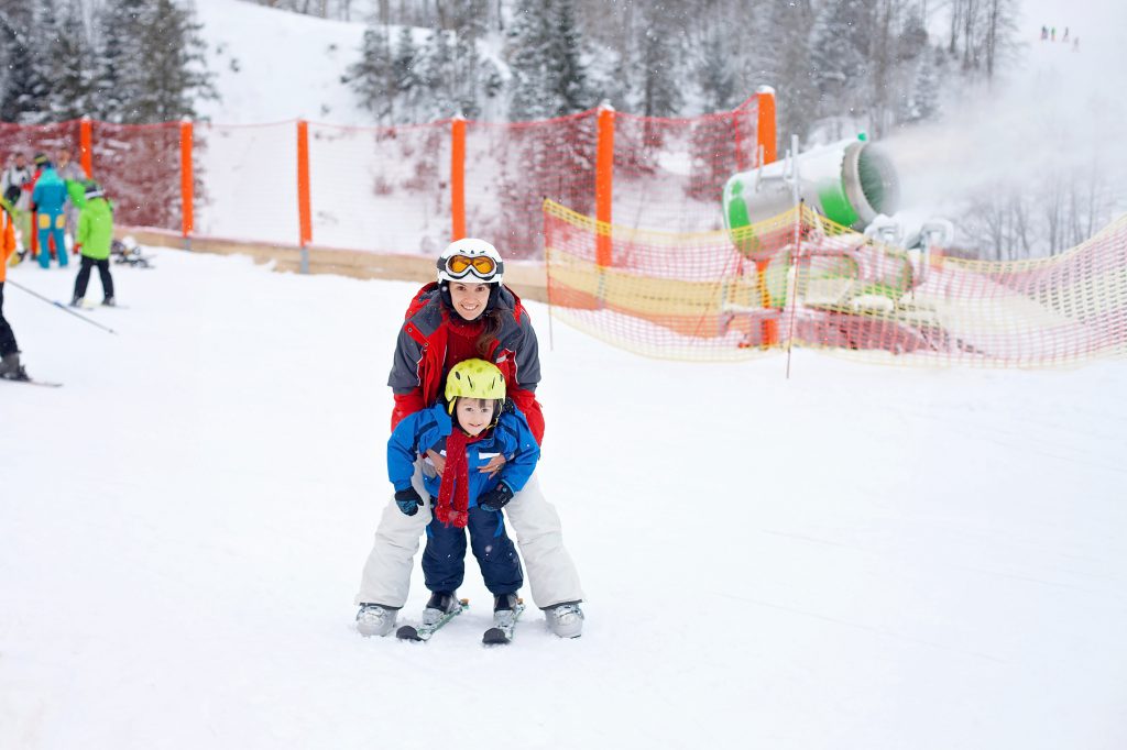 Beautiful young mom and her toddler boy, skiing in the mountains, winter time