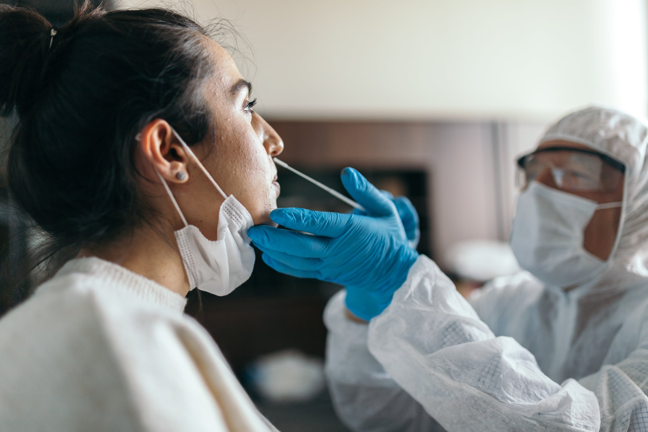 woman receive nose swab for COVID-19 testing