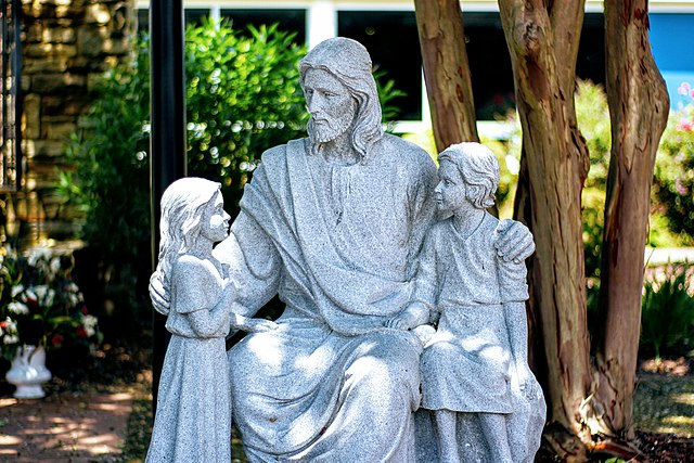 Statue of Jesus seated in the middle of two children