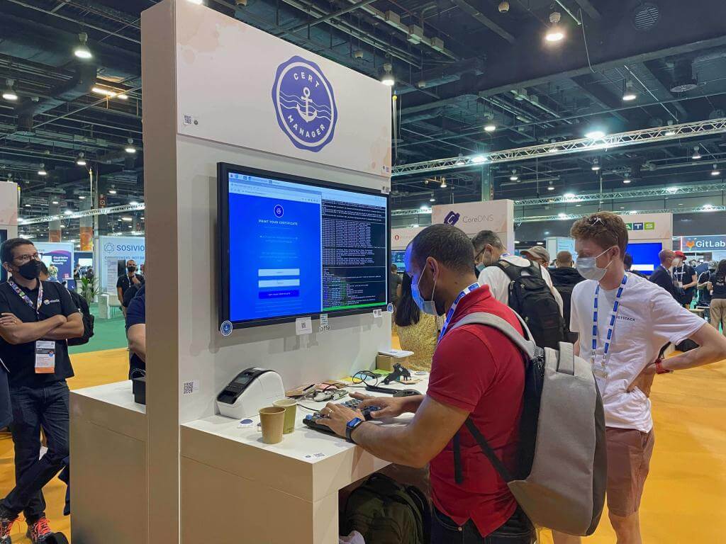 Photo of the cert-manager booth when we were running the Print your certificate experiment. A participant can be seen typing their name and email on the keyboard.