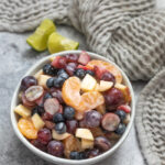 Greek yogurt creamy fruit salad with apples, blueberris, grapes, mandarins and strawberries in a bowl