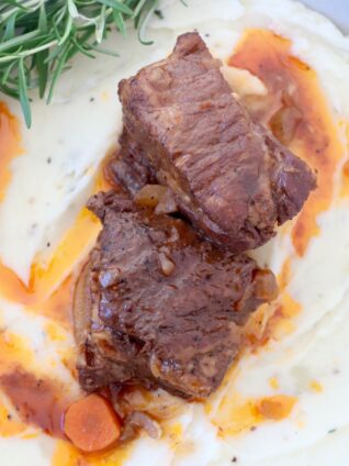 braised short ribs in bowl with mashed potatoes and fresh rosemary