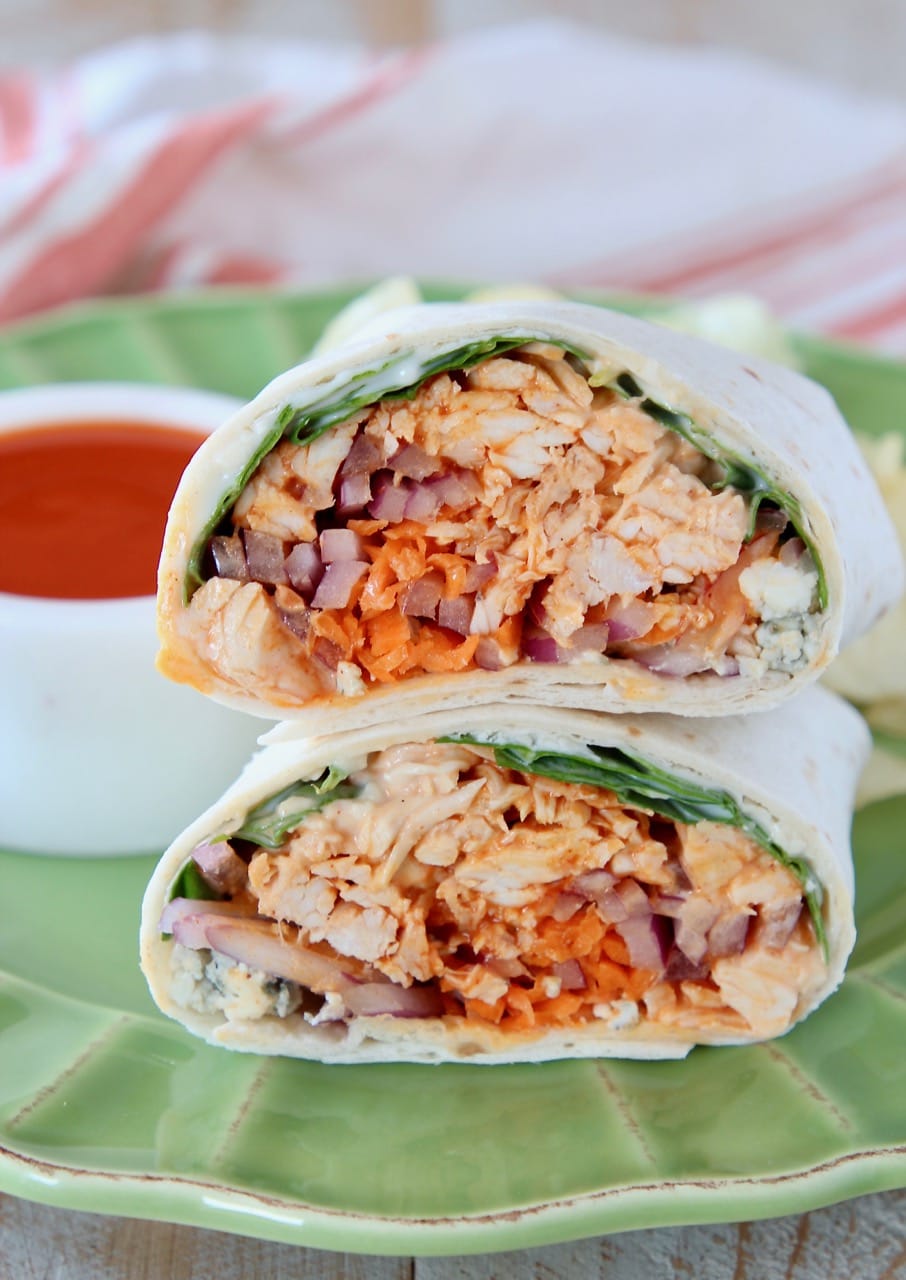 Buffalo chicken wrap sliced in half, sitting on top of each other on a green plate