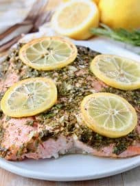 Baked salmon on plate with lemon slices and rosemary sprigs