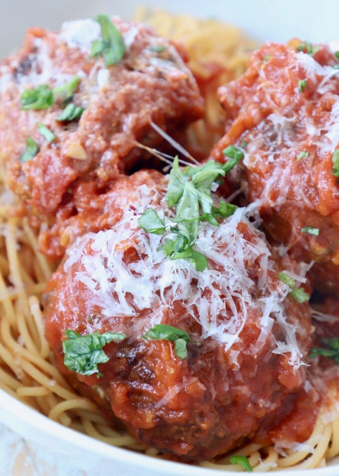 large Italian meatballs in marinara sauce in bowl with spaghetti