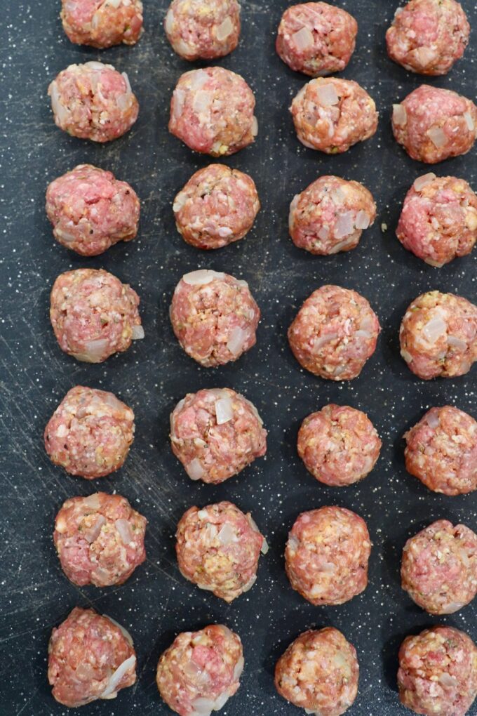 uncooked meatballs on black cutting board