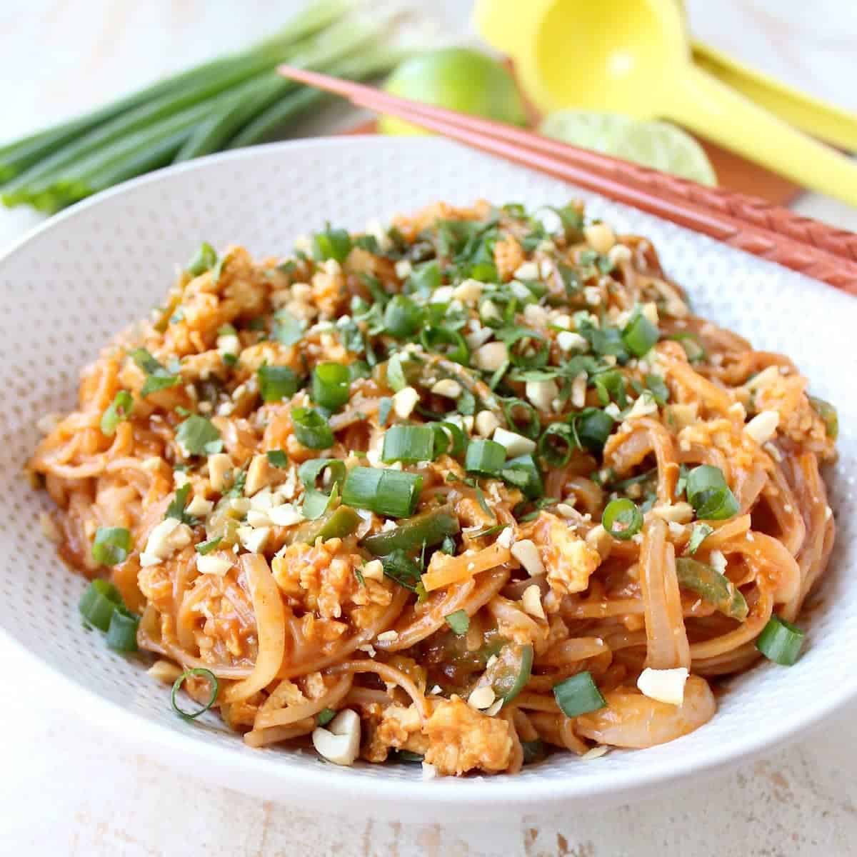 prepared pad thai in bowl with chopsticks on the side