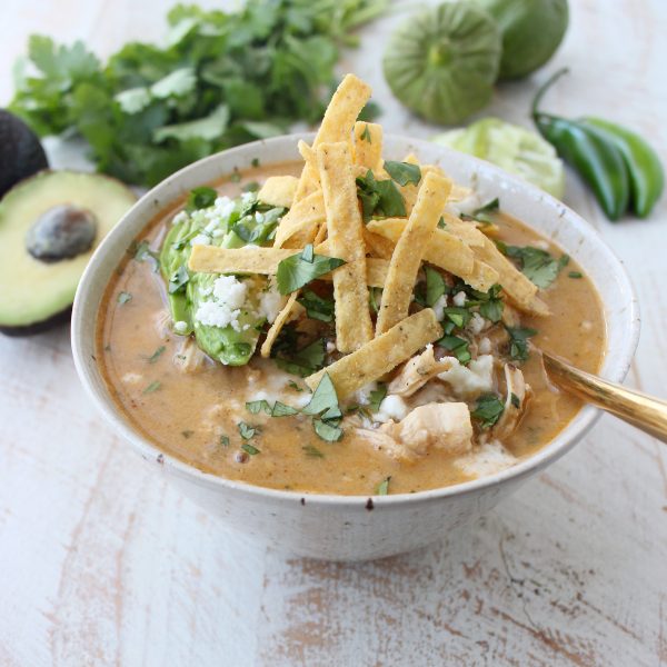 Green Chili Chicken Enchilada Soup in a bowl topped with tortilla strips. 