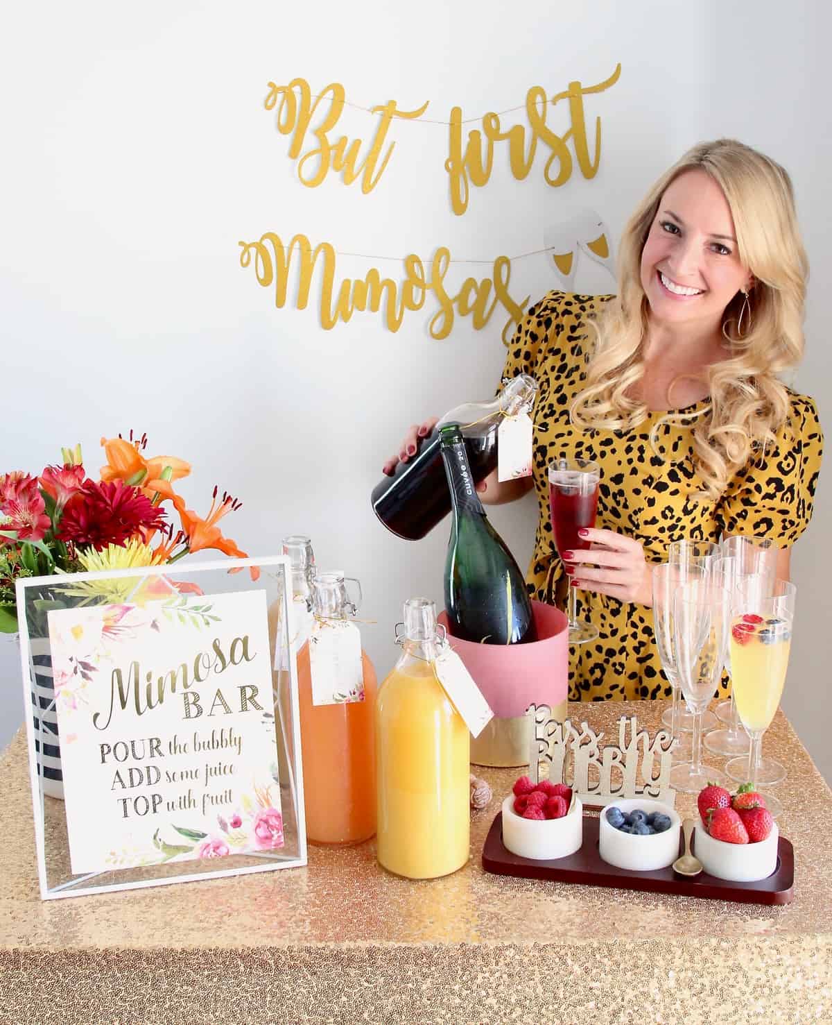 Woman pouring juice into a mimosa standing behind a mimosa bar