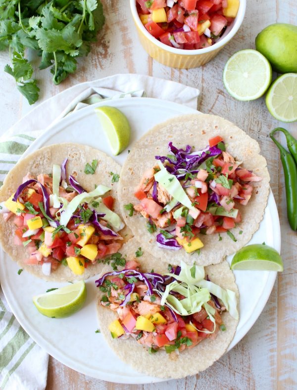 Chipotle honey glazed salmon is placed in warm corn tortillas & topped with fresh mango salsa in this mouth-watering recipe for healthy salmon tacos!