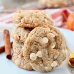 Pumpkin spice white chocolate chip cookies stacked up on a plate