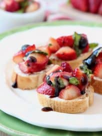 Strawberry bruschetta on white plate, topped with balsamic glaze