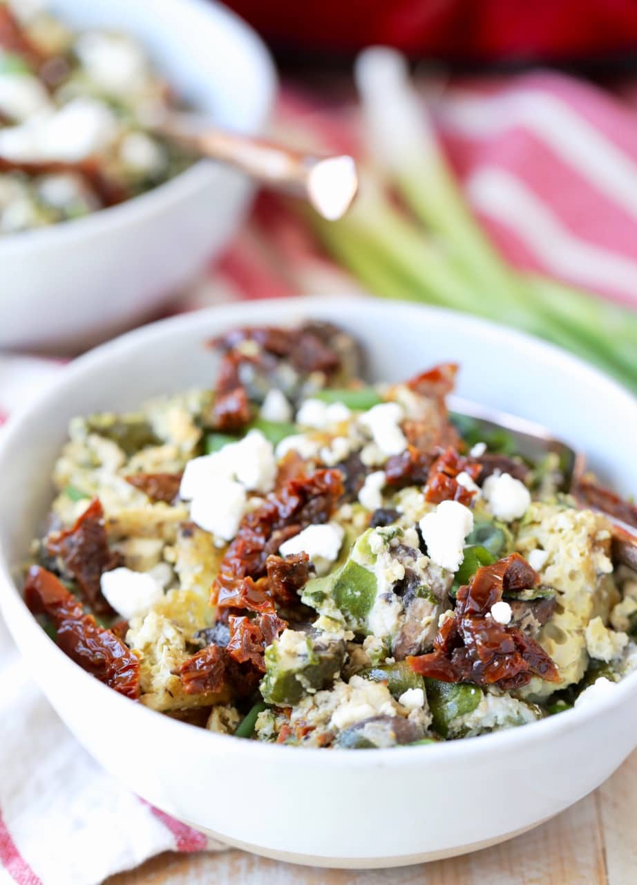 Greek eggs with feta cheese and sun dried tomatoes in bowl