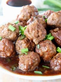 Korean BBQ Meatballs on plate with korean bbq sauce and diced green onions