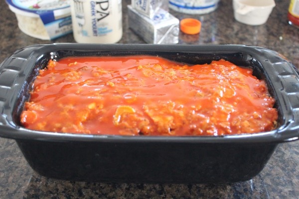 Buffalo Chicken & Pork Meatloaf covered with buffalo sauce in a black loaf pan. 