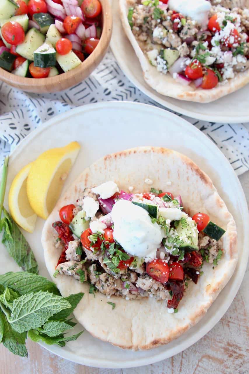 Ground turkey tacos in pita bread on plate, topped with tzatziki sauce