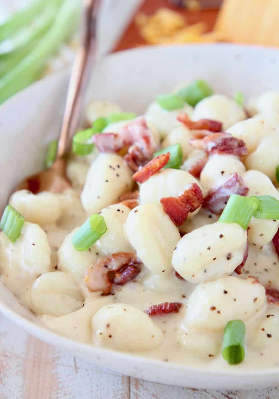 Creamy gnocchi in bowl with spoon